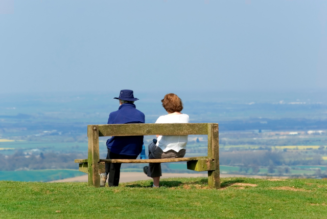 Two people sat on a bench overlooking Gloucestershire countryside 
