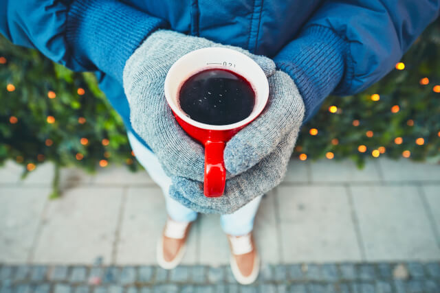 Man wearing gloves and holding cup of mulled wine