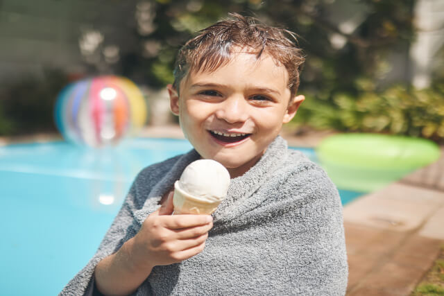 Young boy with ice-cream by the pool